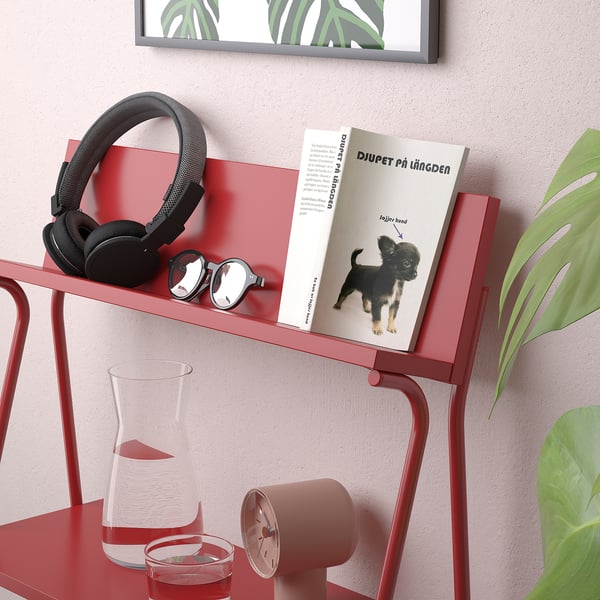 Red metal shelf displays books and items, showing multi-functional storage.
