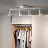 KRUSNATE track lighting holds 4 spots, white. Adjustable lights on a white ceiling, illuminating closet with clothes.