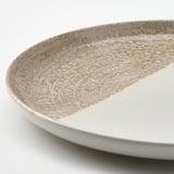 Rustic stoneware plate with speckled glaze. Modern colorblock design, tactile finish.