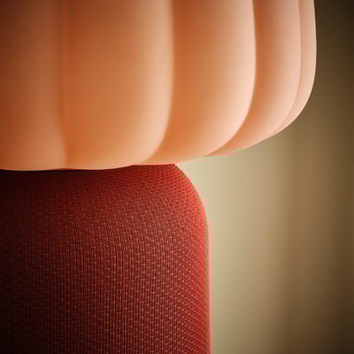 A modern, peach-colored lamp named KULGLASS. The shade is wavy, and the base is textured with a deep red fabric. The design is sleek and contemporary.