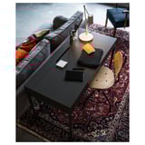 Modern home office: adjustable chair, desk, colorful rug, stationery, lamp, laptop; couch with pillows.