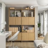 Modern wooden bookshelf, LÅDMAKARE. Light wooden tones, open & closed storage, decorative items, white office chair nearby.