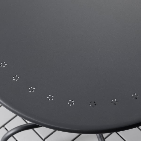 Round black outdoor table with metal legs. Surface has evenly spaced small perforations.