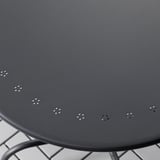 Round black outdoor table with metal legs. Surface has evenly spaced small perforations.