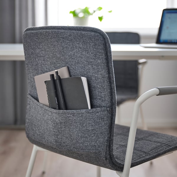 Grey office chair with pocket holding notebooks and pens. Ideal for storing stationery.