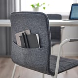 Grey office chair with pocket holding notebooks and pens. Ideal for storing stationery.