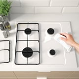 Cleaning a gas stove with a white cloth.