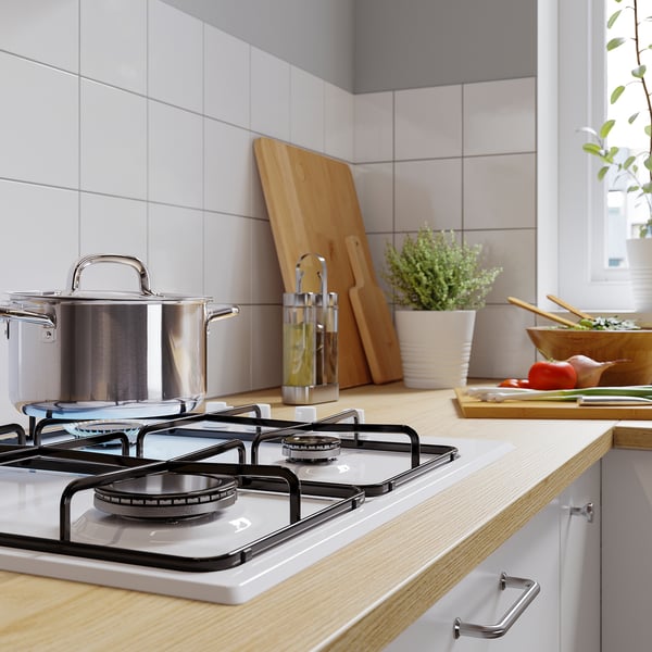 Modern kitchen counter with stove, pots, boards, plant.