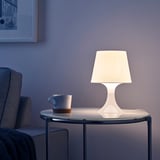 LAMPAN lamp on table next to cup, providing warm, inviting mood light.