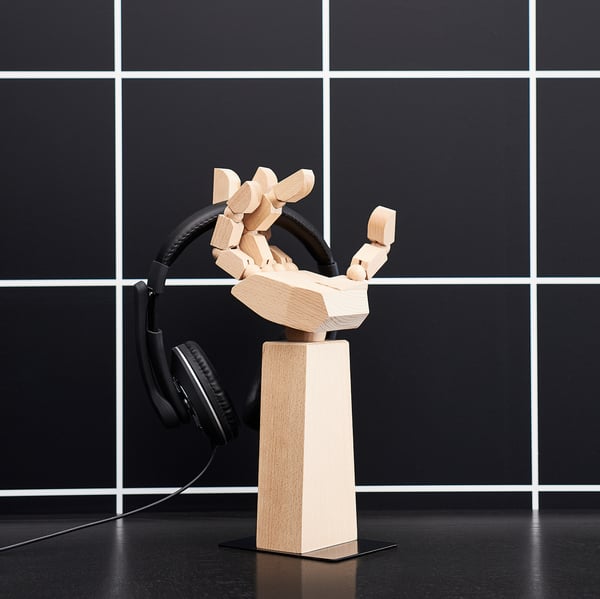 Wooden LÅNESPELARE desk stand in natural color holding black headphones. Elegant, minimalist design.