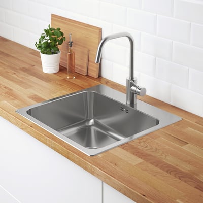 Modern kitchen sink with stainless steel faucet, wooden countertop, plant, and soap.