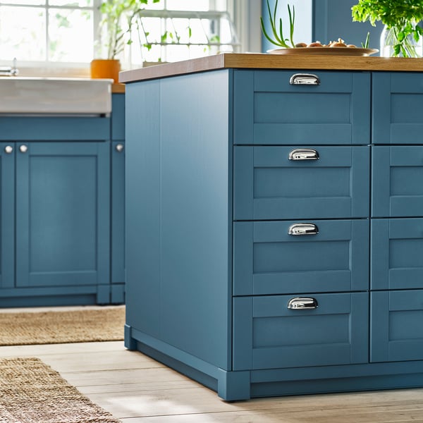 Blue kitchen cabinets with wooden countertop and plants.