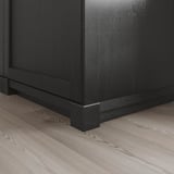 Black wooden kitchen plinth on light floor, showing robust design.