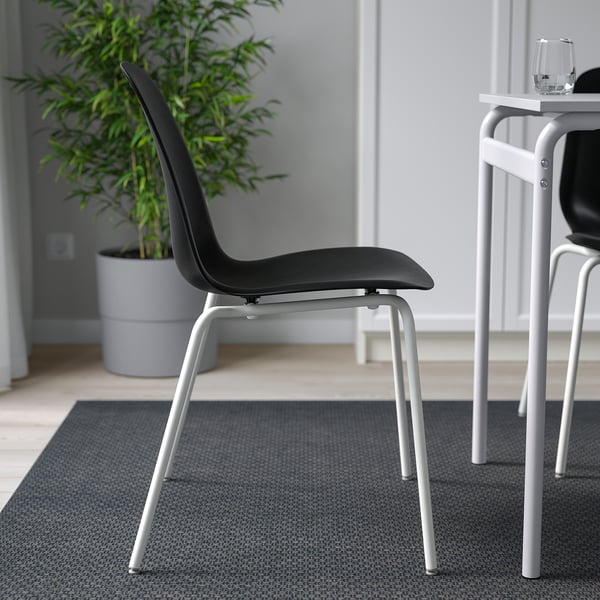 Black chair with white legs, designed for comfort and flexibility. Stackable, easy to clean. Ideal for indoor dining.