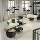 Modern living room with cream sofa, black tables, large windows.