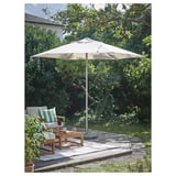 Outdoor patio scene with LINDÖJA beige parasol, wood furniture, cushions, plants, on a deck.