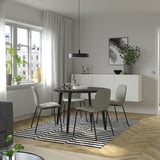 Modern dining area with black LISABO table, grey chairs, striped rug, and plant.