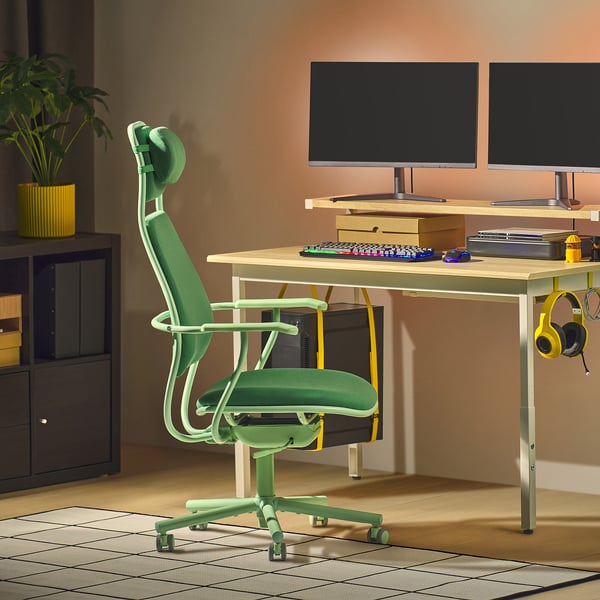 Modern gaming setup with green LÖPARBANA chair, dual monitors, keyboard, and headphones. Chair is larger, with high back and headrest support.
