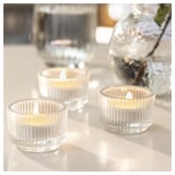 Three lit ribbed glass candles on a table, creating a warm, inviting ambiance.
