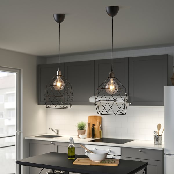 Kitchen with 2 black LUNNOM pendant lights above island, bowl, utensils, oil.