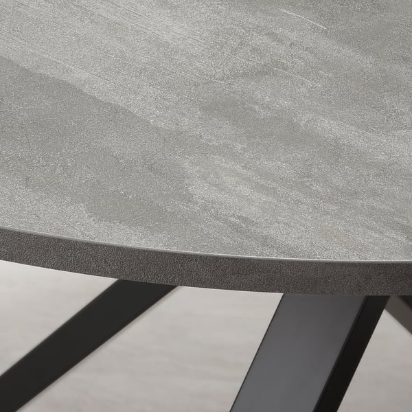 Close-up of a modern round table with smooth edges and a black metal frame, showcasing its sleek, durable design.