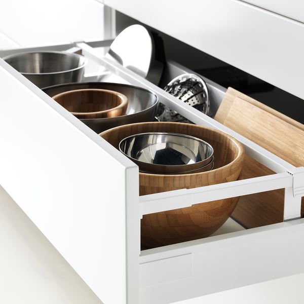 White kitchen drawer fully extended, displaying organized containers: two stainless steel bowls, two wooden bowls, and a wooden cutting board.