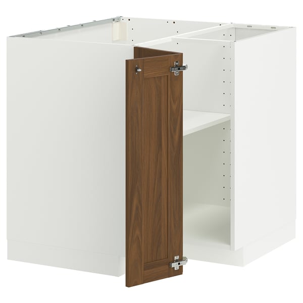 A white METOD kitchen cabinet with a walnut-brown door open. Its a corner base unit with metal hinges.