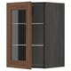 A METOD kitchen cabinet with walnut-finished glass doors and dark frame, featuring adjustable shelves.
