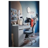 Modern workspace with MICKE desk & grey chair. Desk has drawers, shelf, & pegboard with notes and items. Blue wall a basketball hoop.