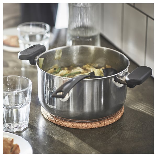 Cooking with veggies on stove, cups nearby.