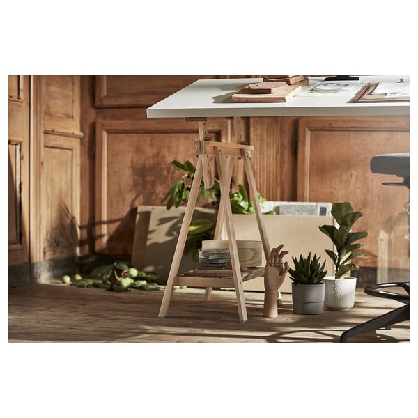 Wooden desk setup with white tabletop and light-colored legs. Includes plants and paper on the table.
