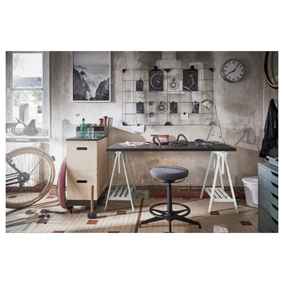 Modern industrial desk & stool. Black desk, white legs, grey stool, tiled floor, clock, bike.
