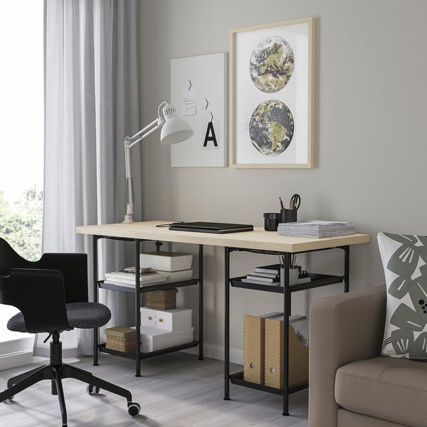 Home office setup featuring MITTCIRKEL desk with pine top & black legs, black chair, lamp, globe art, and couch with pillow.