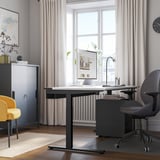 Modern home office with MITTZON adjustable desk, grey chair, yellow accent chair, window, and map.