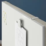 Whiteboard screen with hooks and papers attached.