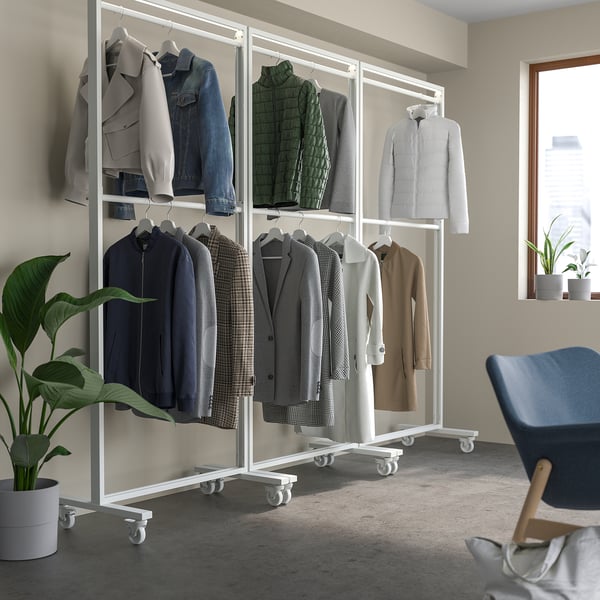Modular coat rack with jackets, near plant and blue chair.