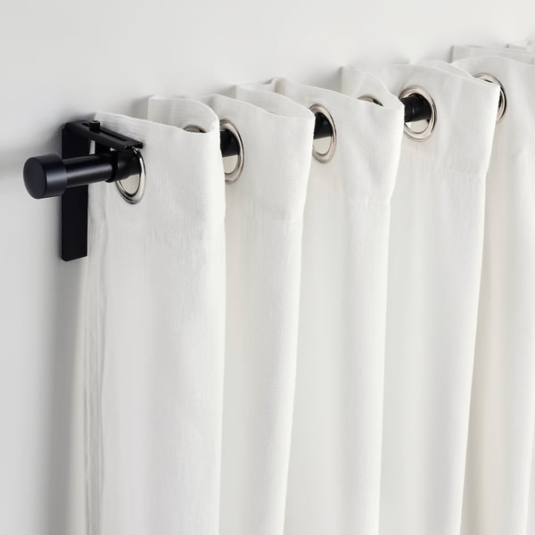 White curtains with silver eyelets hang on black rods, providing privacy and filtering light.