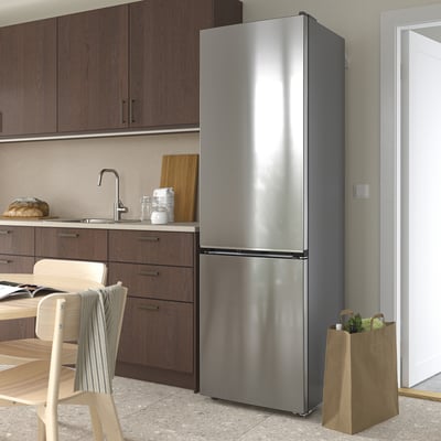 Modern kitchen with stainless steel MÖLNÅS fridge freezer, wooden chair, bread, and grocery bag near door.