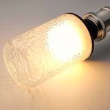 Close-up of a light bulb with a hammered glass texture, emitting a soft, warm glow.