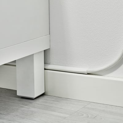 A section of white skirting board with a cable trunking attached, demonstrating a neat solution for hiding and organizing cables along the wall base.