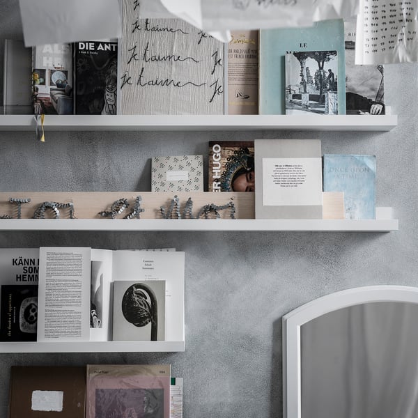 White shelves with books, photos, & decor. Some books open, black & white images.