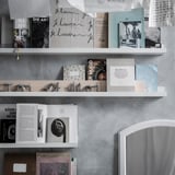 White shelves with books, photos, & decor. Some books open, black & white images.