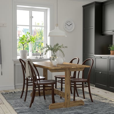Cozy dining area with wooden table, chairs, pendant lamp, and decorative vase.