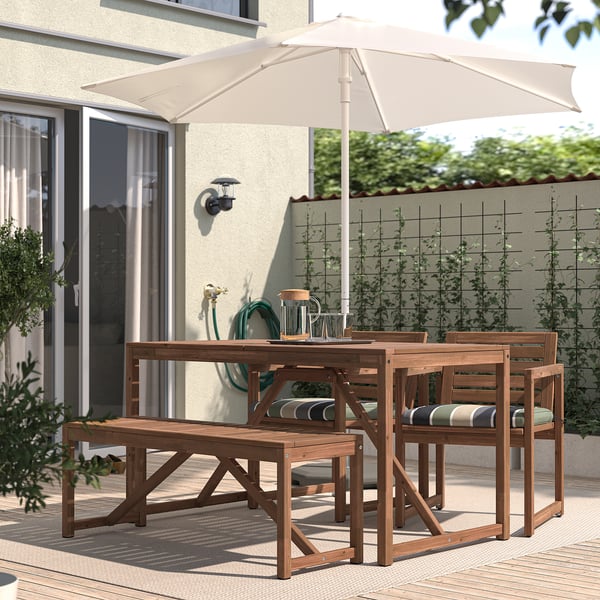 Wooden patio dining set with umbrella & cushioned chairs.