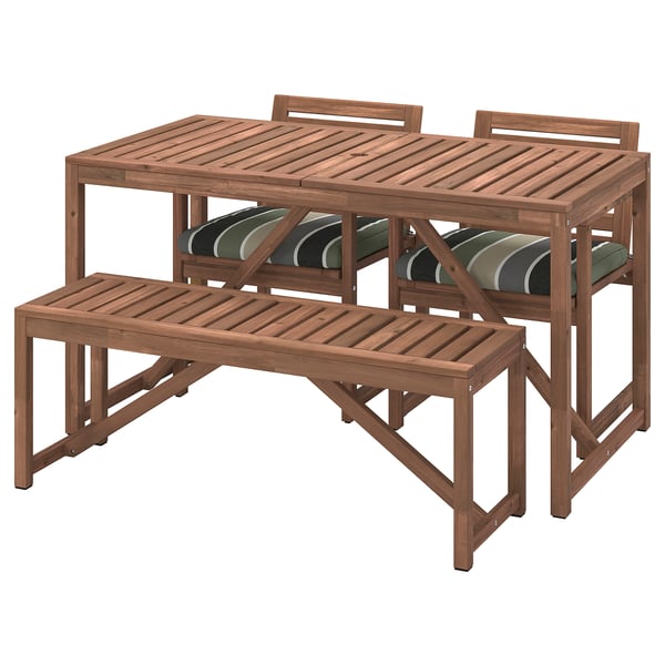 Brown acacia wood outdoor table, bench, and two chairs. Stripes on cushions.
