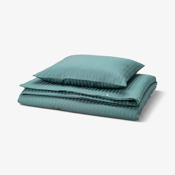 A folded greenish-blue bedding set, featuring a duvet and pillowcases with subtle stripes, neatly stacked, showcasing its smooth, sateen fabric.