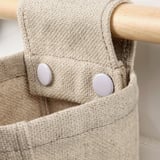 Close-up of natural fiber storage basket with sturdy wood pole and durable fabric.