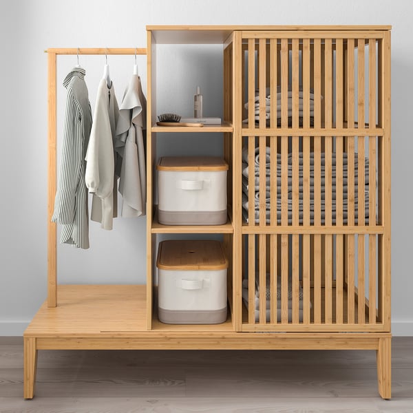Light wood wardrobe with clothes and storage bins, fits against wall or under shelves.