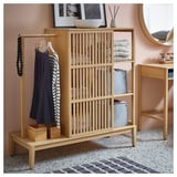 NORDKISA light wood storage unit with clothes and decor.