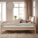 A modern bedroom a NORDLI bed frame with beige tones, light wood material, and soft, plush bedding.